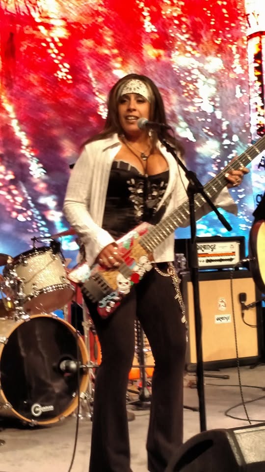 Merry Adin singing and playing bass in a white jacket