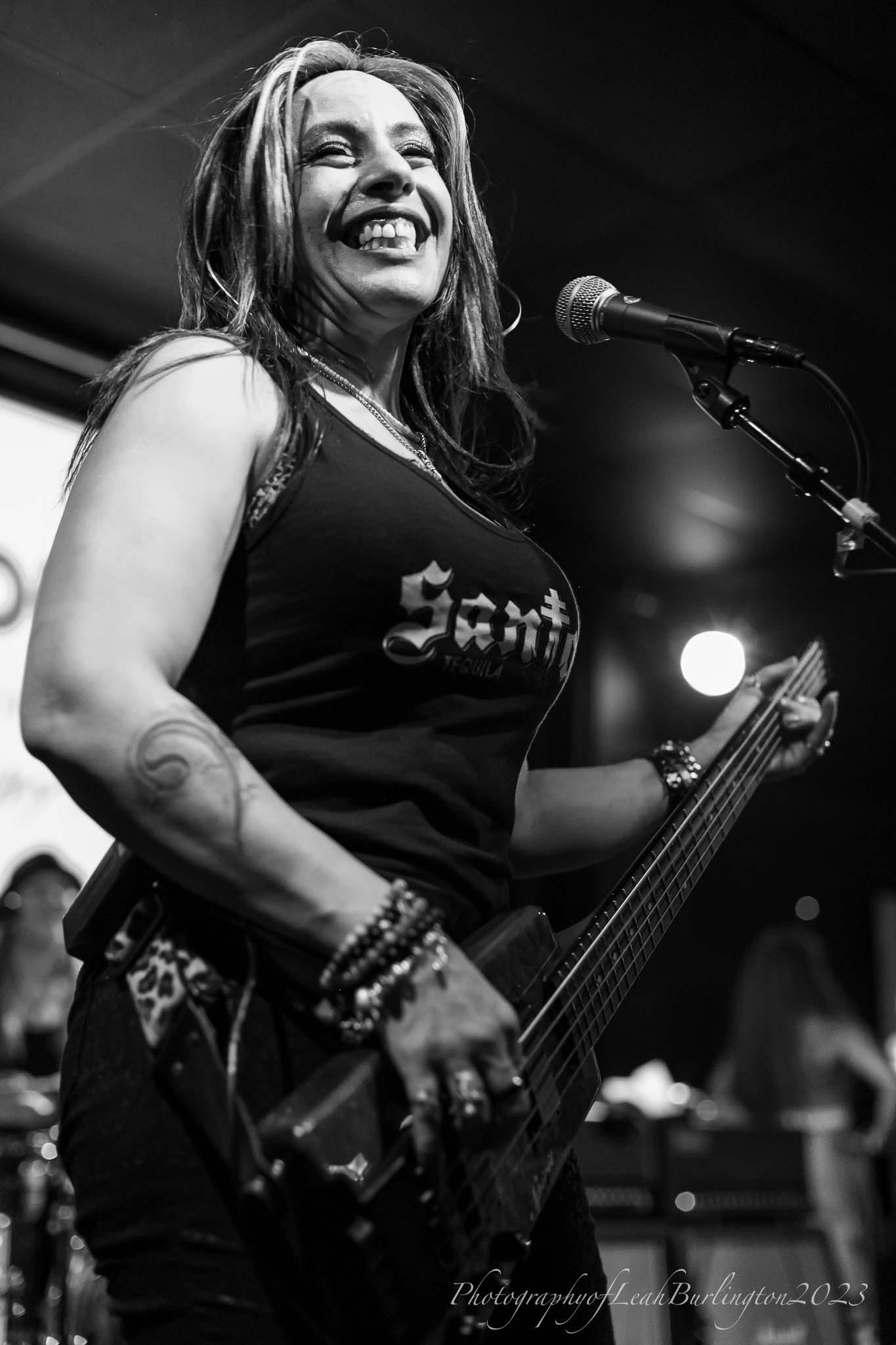 Merry Adin smiling onstage while playing bass