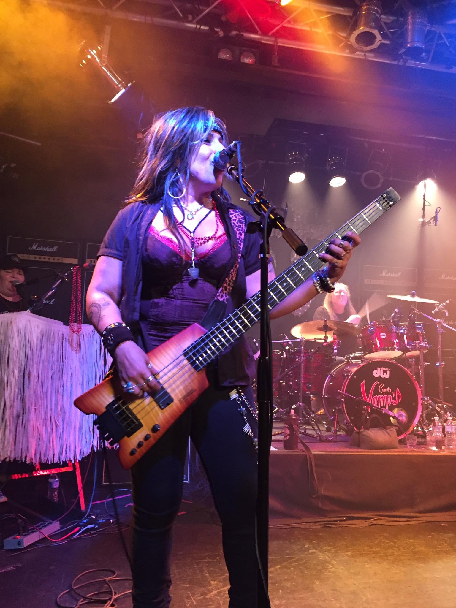 Merry Adin performing with her band under multicolored stage lights